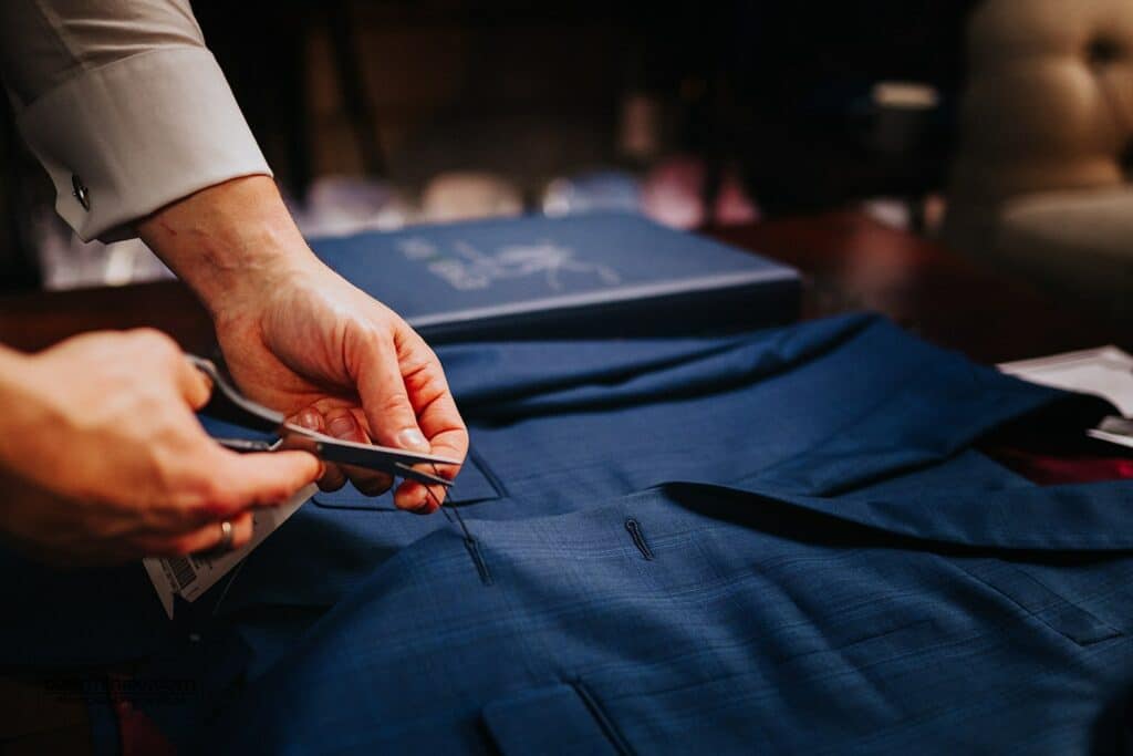 Tailor cutting label off a navy bespoke suit